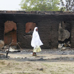 A woman walks past burned houses in the remote town of Baga, northern Nigeria, on April 21, 2013.