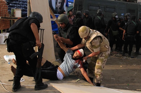An injured supporter of ousted Muslim Brotherhood president Mohamed Morsi is carried away by his military assailants on 14 August 2013 