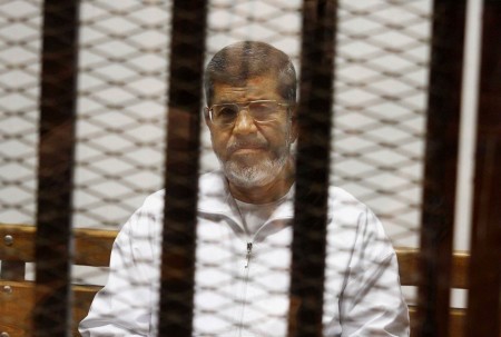 Mohamed Morsi peers from behind the bars of a soundproof cage during his sentencing this week