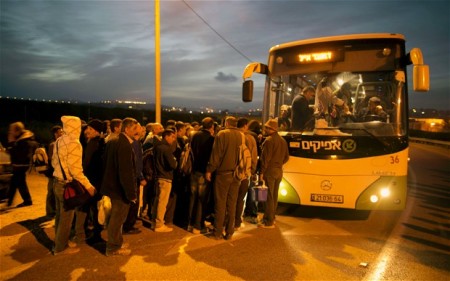 Palestinians queue to board a bus made available by Israel to take Palestinian labourers from the Israeli army crossing Eyal, near the West Bank town of Qalqilya, into Tel Aviv in 2013