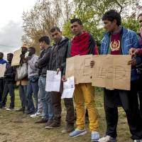 : Migrants in Calais protest during a visit to their camp by the French interior minister
